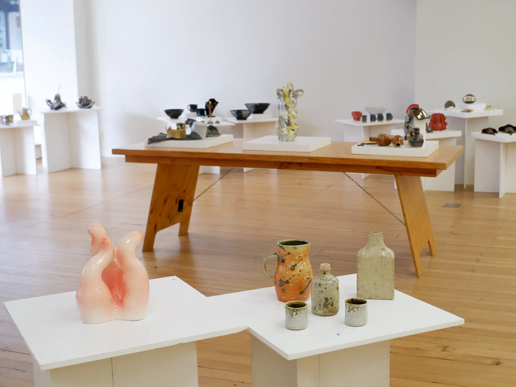 Glazed ceramic vessels and sculptural work arranged across exhibition plinths