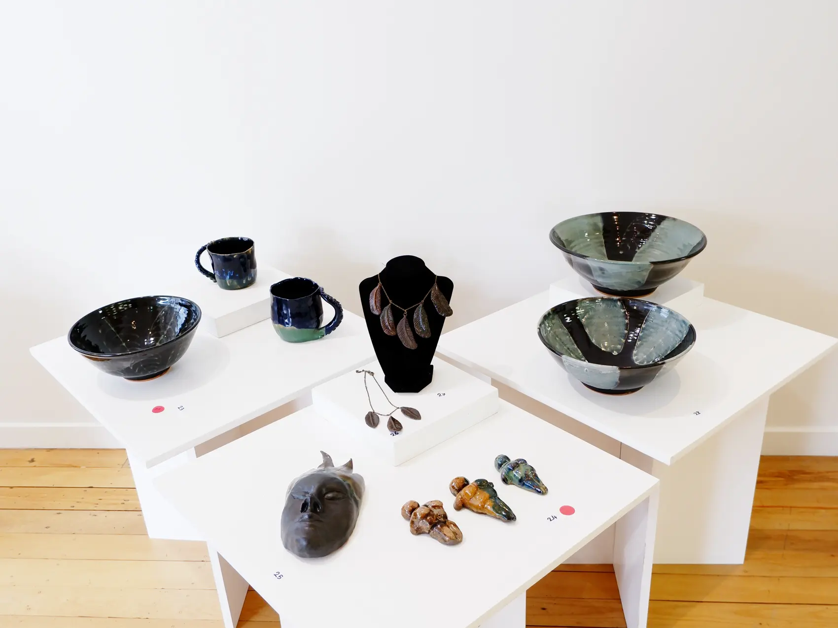 Glazed ceramic vessels and sculptural work arranged across exhibition plinths