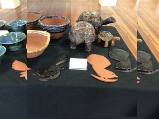 Ceramic figures and vessels displayed together on white plinths